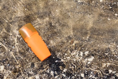 Photo of Bottle with sun protection spray on seashore, top view. Space for text