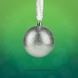 Image of Beautiful silver Christmas ball hanging on green background