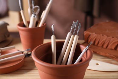 Photo of Set of different clay crafting tools on wooden table in workshop, closeup