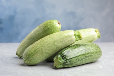 Fresh ripe zucchini on grey table against blue background