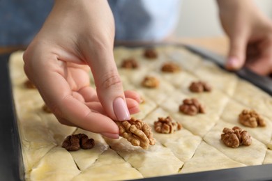 Making delicious baklava. Woman putting walnut onto dough, closeup