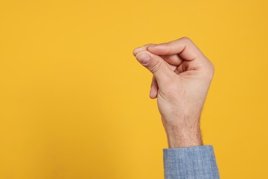 Photo of Man snapping fingers on yellow background, closeup of hand. Space for text