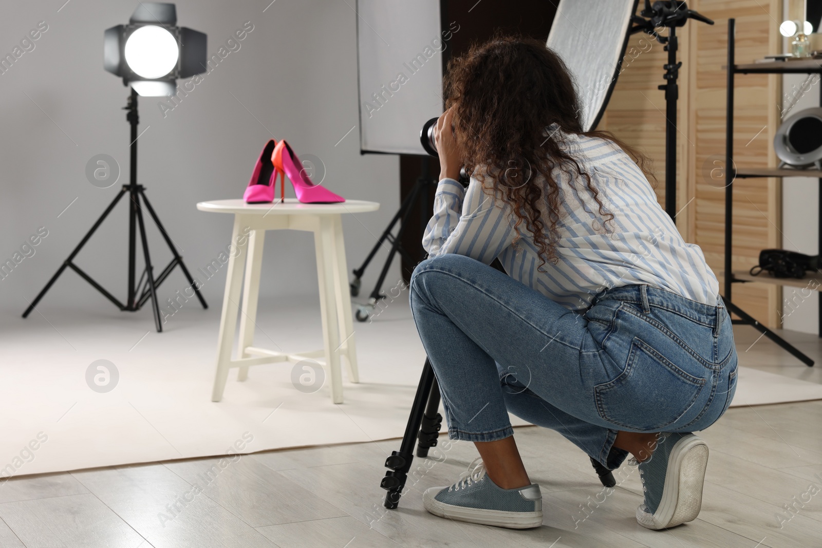 Photo of Professional photographer taking picture of stylish shoes in studio