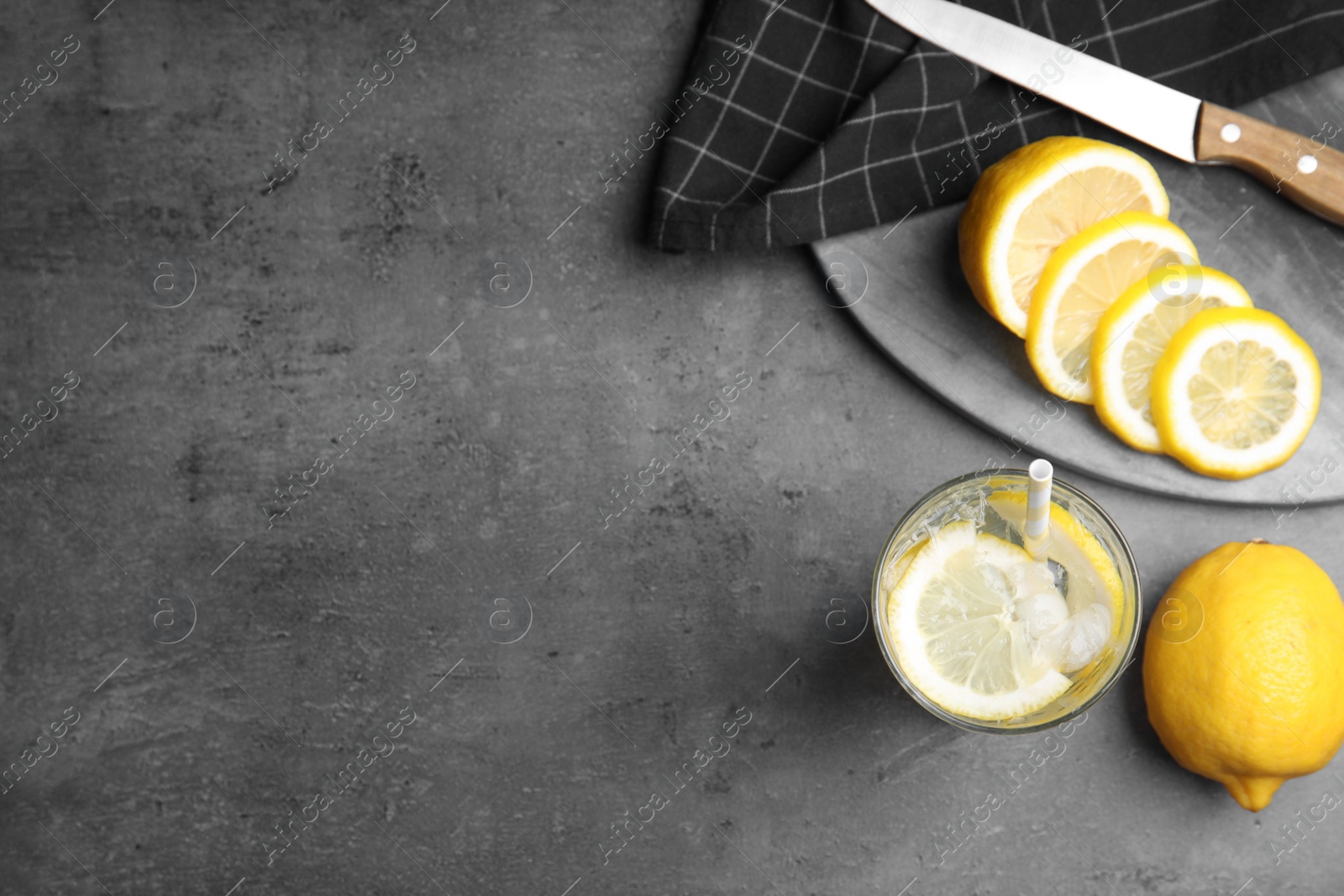 Photo of Soda water with lemon slices and ice cubes on grey table, flat lay. Space for text