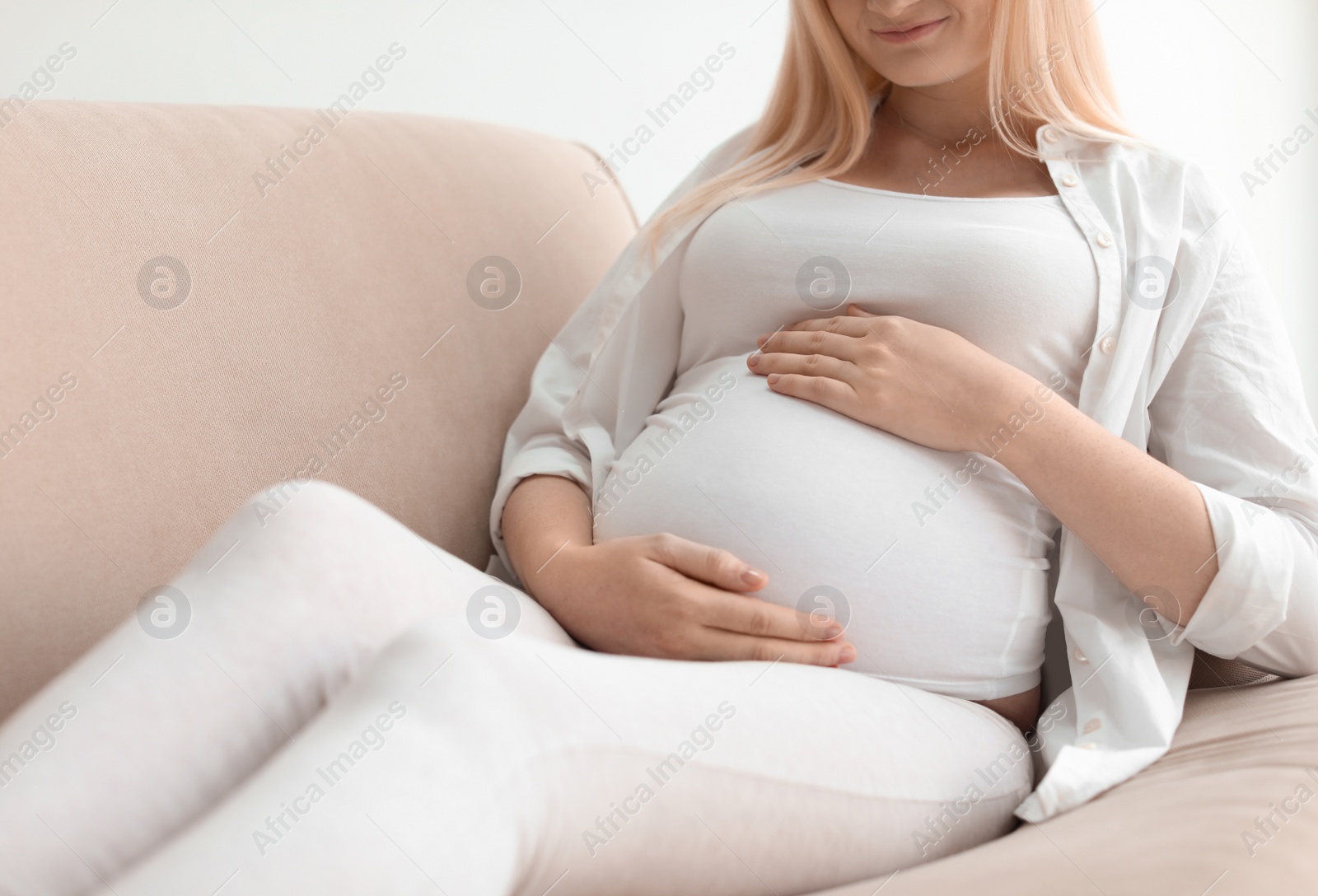 Photo of Pregnant woman resting on sofa at home, closeup