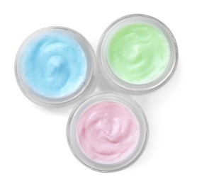 Jars of different body creams on white background, top view