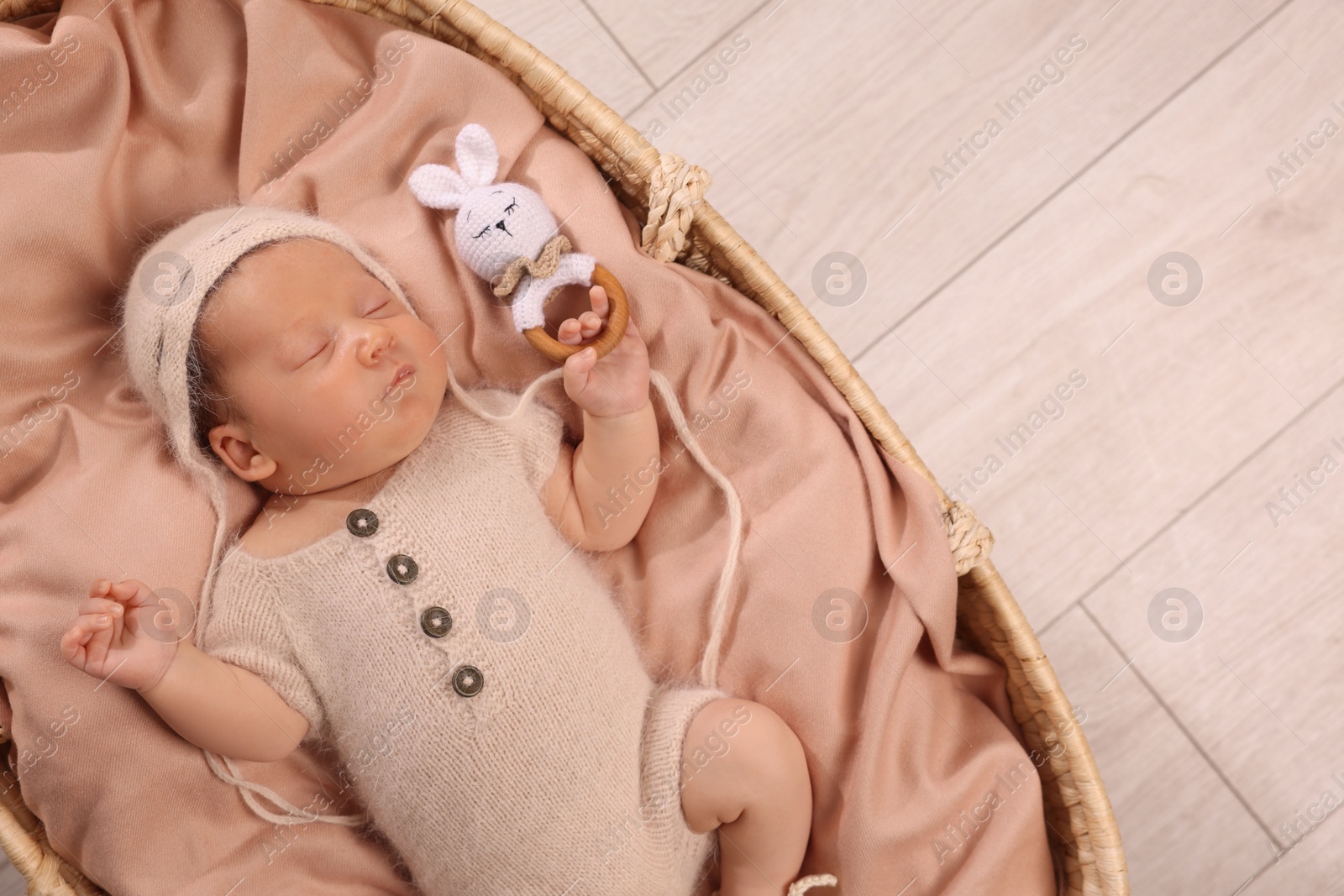 Photo of Cute newborn baby sleeping with rattle in wicker crib indoors, top view. Space for text