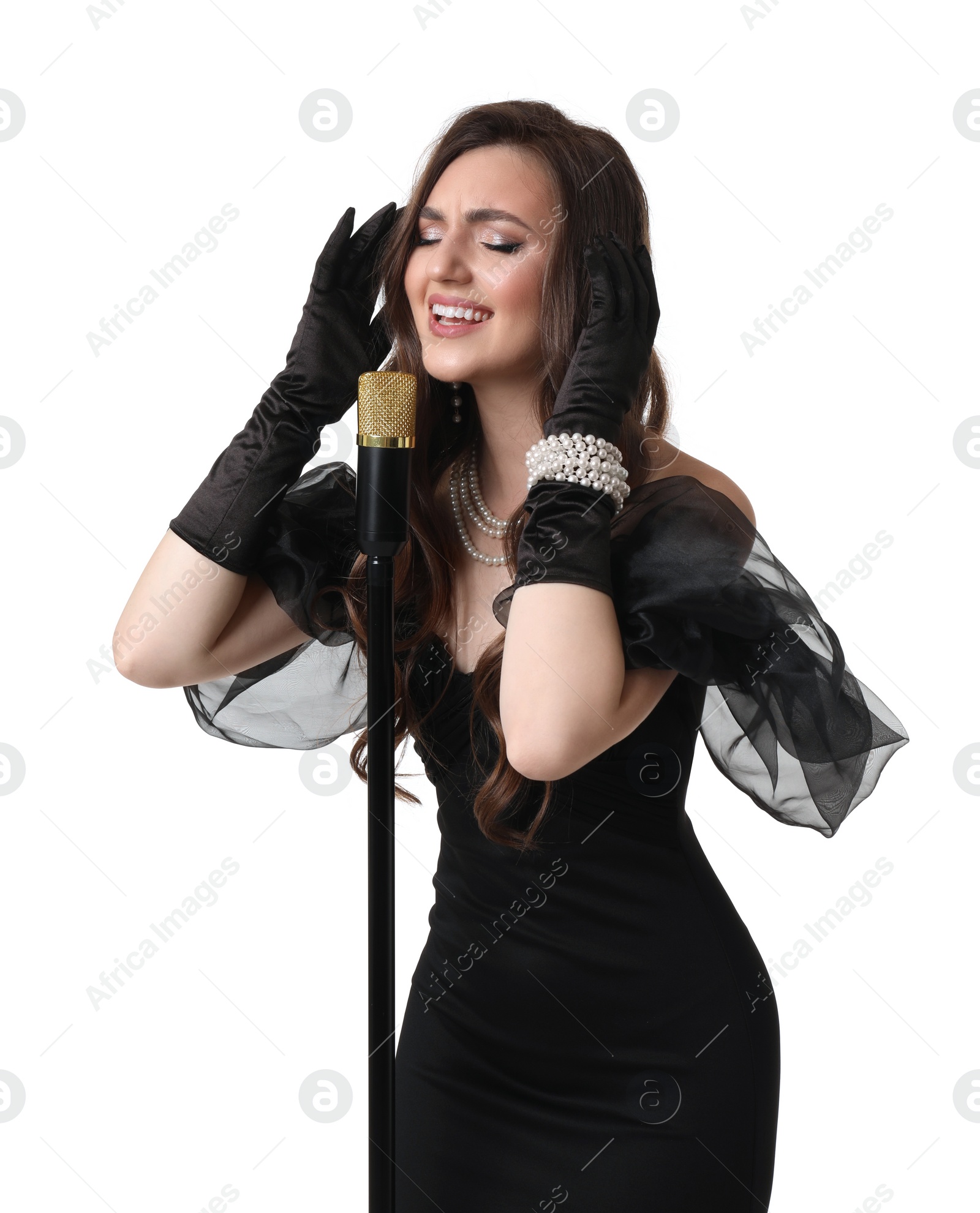 Photo of Beautiful young woman in stylish black dress with microphone singing on white background