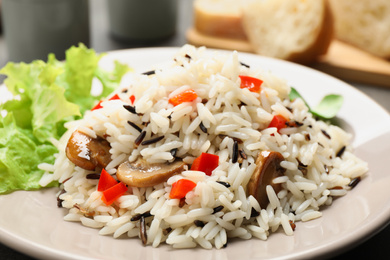 Photo of Delicious rice pilaf with mushrooms on plate, closeup