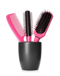 Hairbrushes and comb in holder on white background