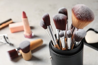 Photo of Setprofessional brushes and makeup products on grey table, closeup. Space for text