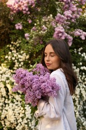 Photo of Attractive young woman with lilac flowers outdoors