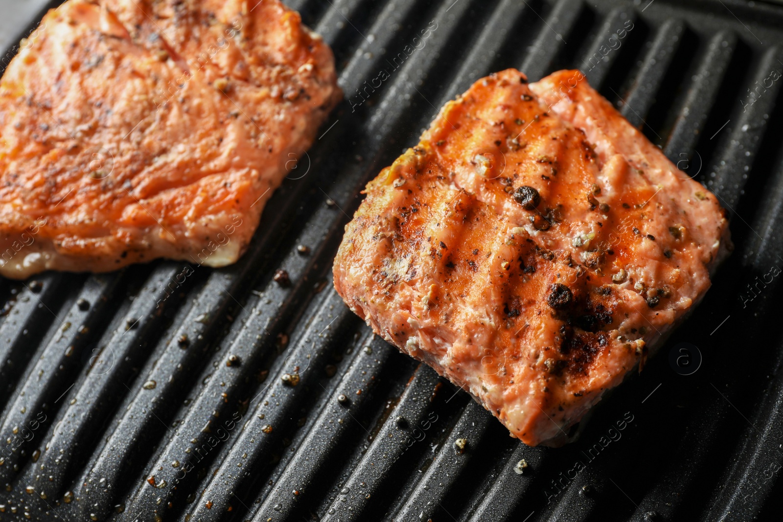 Photo of Tasty salmon cooking on electric grill, closeup