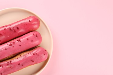 Photo of Delicious eclairs covered with glaze on pink background, top view. Space for text