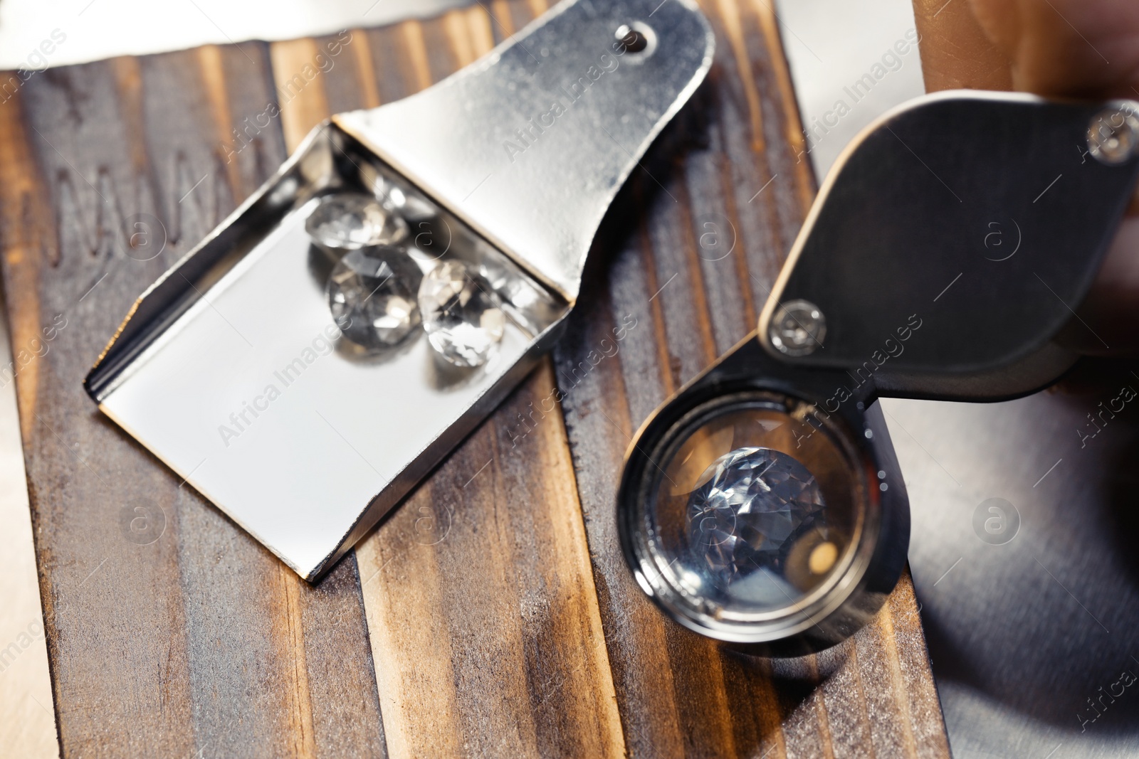 Photo of Professional jeweler working with gemstone at wooden table, closeup