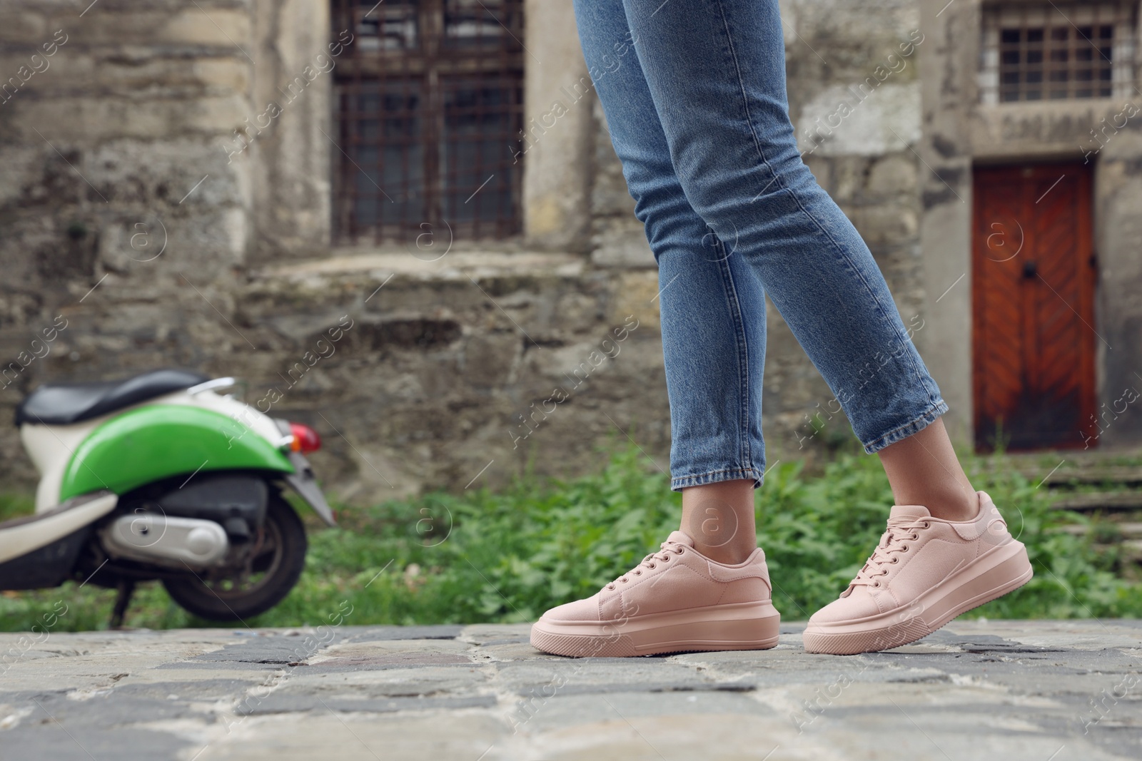 Photo of Woman in stylish sneakers walking on city street, closeup. Space for text