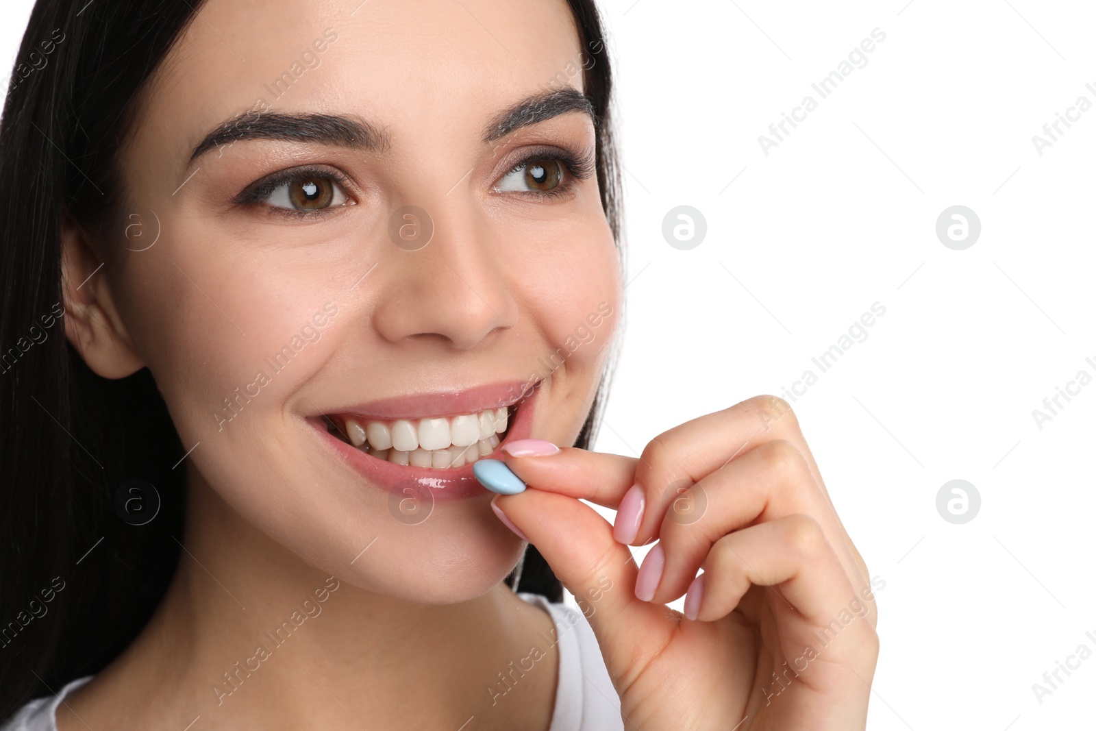 Photo of Young woman taking vitamin pill on white background, closeup