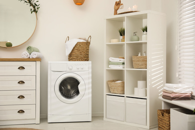 Photo of Modern washing machine near white wall in elegant bathroom