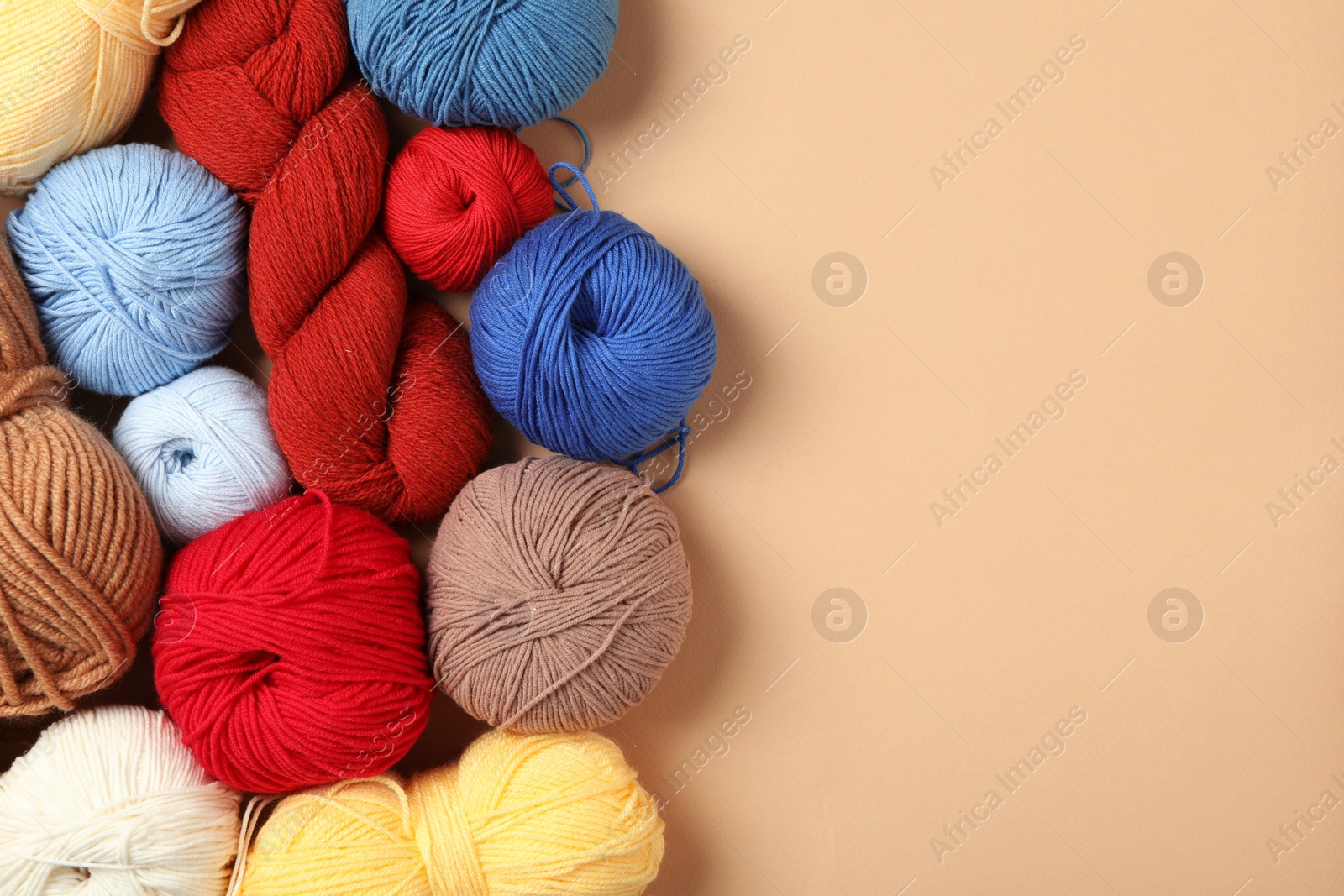 Photo of Soft woolen yarns on beige background, flat lay. Space for text