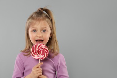 Photo of Portrait of cute girl with lollipop on light grey background. Space for text