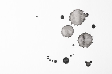 Photo of Blots of black ink on white background, flat lay. Space for text