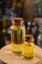 Bottles with herbal essential oils on blurred background