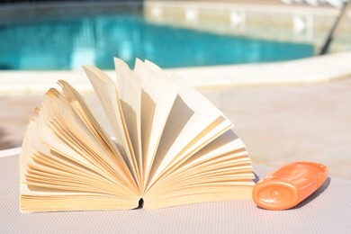 Photo of Open book on deck chair near swimming pool