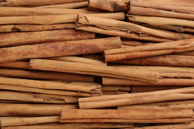 Photo of Aromatic cinnamon sticks as background, top view