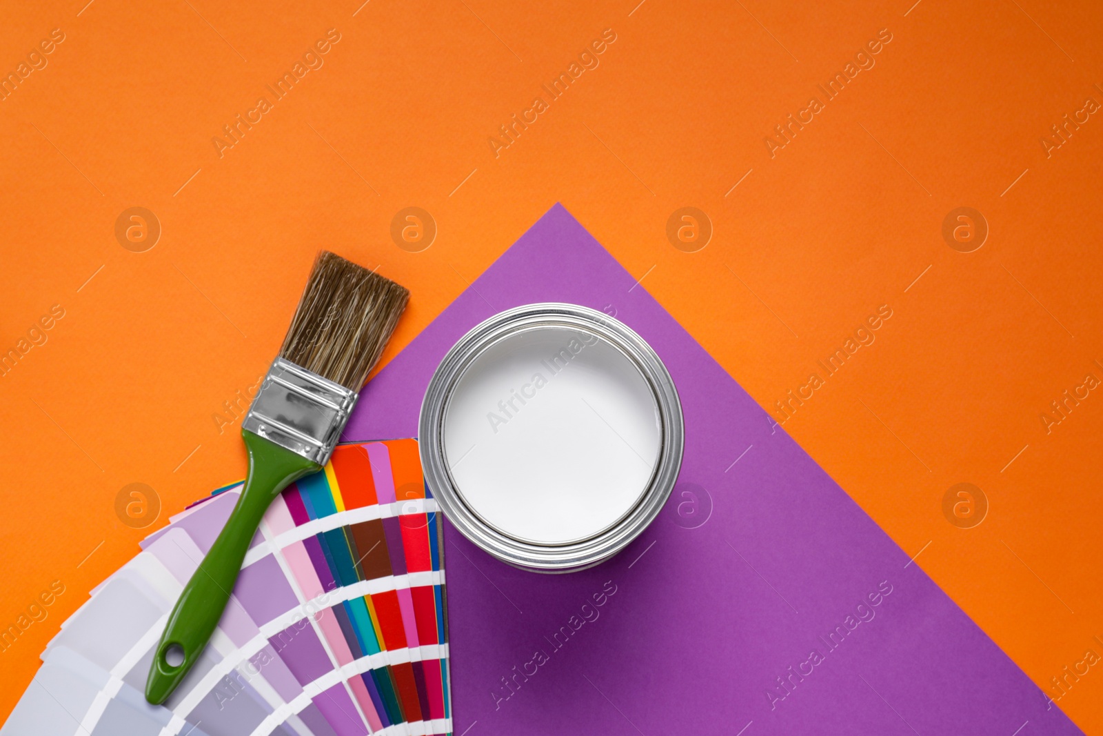 Photo of Can with white paint, color palette and brush on color background, flat lay