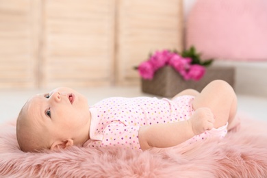 Adorable baby girl lying on fluffy rug