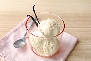 Photo of Glass with tasty vanilla ice cream on wooden background