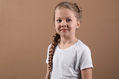 Little girl with braided hair on light brown background