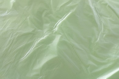 Texture of light green plastic bag as background, closeup