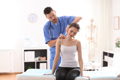 Photo of Male orthopedist examining patient's neck in clinic
