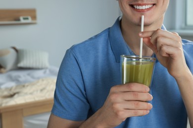 Photo of Young man drinking juice in bedroom, closeup