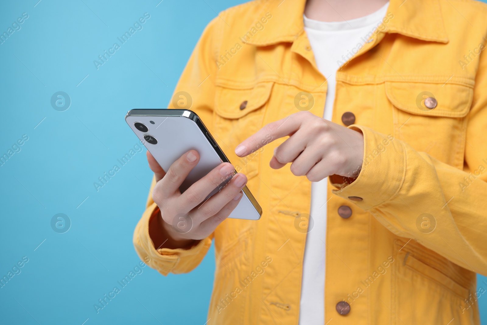 Photo of Woman sending message via smartphone on light blue background, closeup