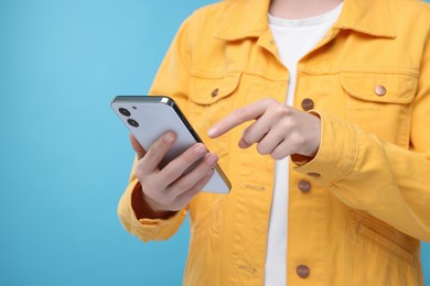 Photo of Woman sending message via smartphone on light blue background, closeup