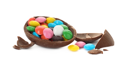 Photo of Broken chocolate egg with colorful candies on white background