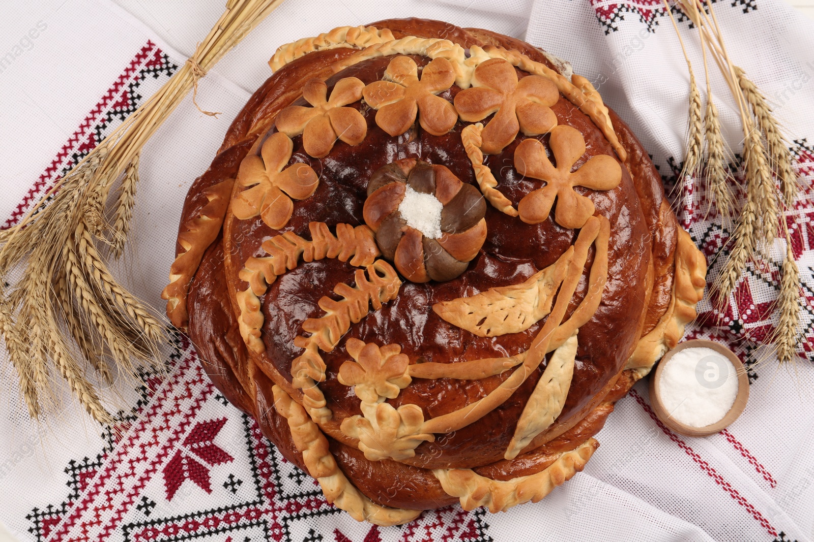 Photo of Korovai with wheat spikes on rushnyk, above view. Ukrainian bread and salt welcoming tradition