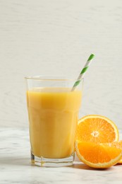 Glass of orange juice and fresh fruits on white marble table