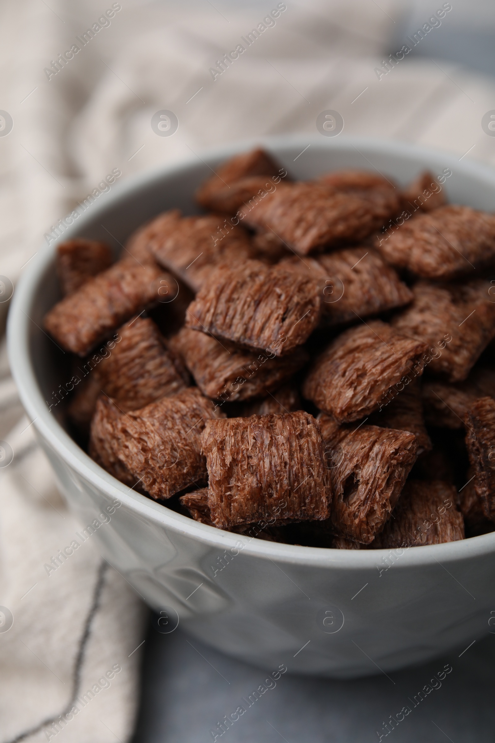 Photo of Chocolate cereal pads in bowl on grey table, closeup