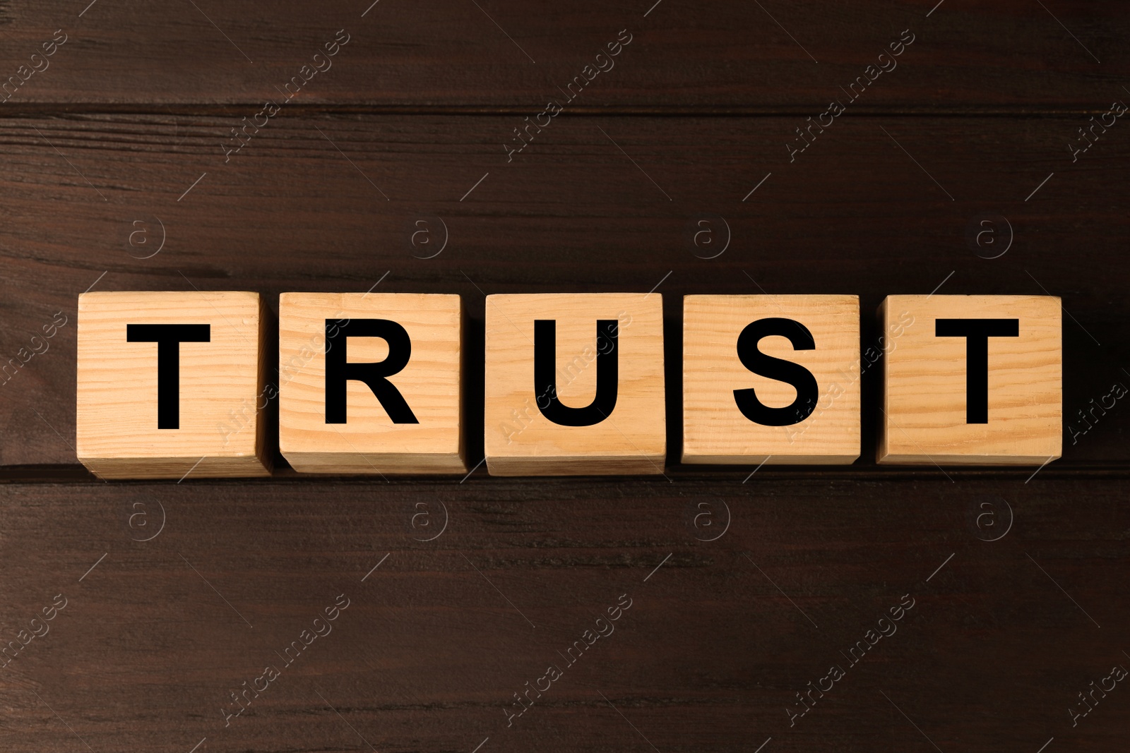 Photo of Cubes with word TRUST on wooden table, flat lay