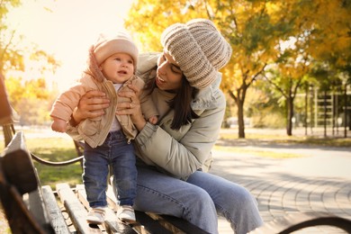 Photo of Happy mother with her baby son on bench in autumn park