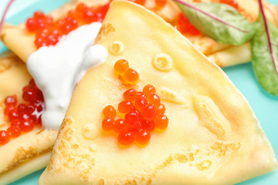 Photo of Delicious pancakes with caviar and cream, closeup