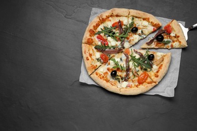 Tasty pizza with anchovies, arugula and olives on black table, top view. Space for text