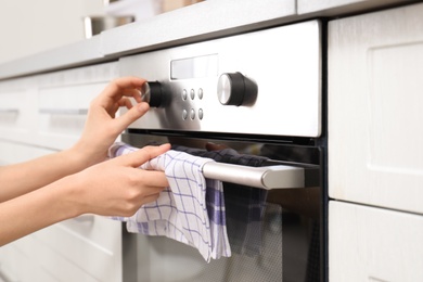 Photo of Young woman adjusting oven settings in kitchen, closeup