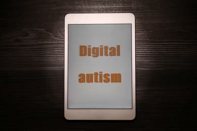 Tablet with phrase Digital Autism on wooden table, top view. Addictive behavior