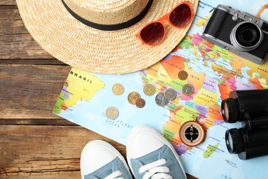 Photo of Flat lay composition with world map and different travel accessories on wooden table. Planning summer vacation trip