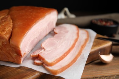 Photo of Delicious smoked bacon and garlic on wooden table, closeup