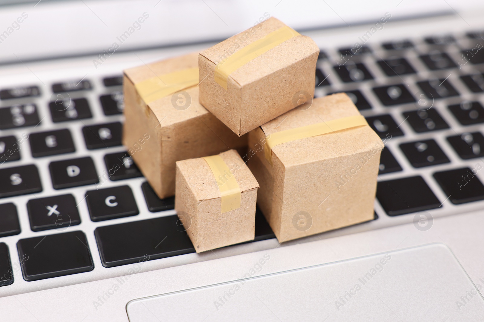 Photo of Internet shopping. Small cardboard boxes on laptop, closeup